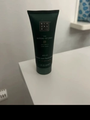 Rituals The Ritual of Jing handkräm - Handkräm från Rituals, The Ritual of Jing-serien. Tuben är mörkgrön med vita och guldiga detaljer och innehåller 40 ml. Produkten är en instant care hand lotion som passar alla hudtyper och har en avslappnande doft.