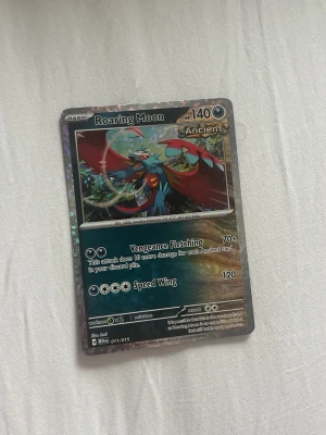 Pokémonkort Roaring Moon holo - Säljer ett Pokémonkort med motivet Roaring Moon. Kortet är holografiskt och har färger som svart, röd, blå och grön. Det är en Ancient-korttyp med 140 HP och attacker som Vengeance Fletching och Speed Wing. Perfekt för samlare eller Pokémonfans.chat got sa det var värt 80 kr 