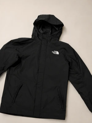 The North Face Windbreaker - The North Face DryVent Windbreaker Jacket 📏 Kids XL (14/16) – fits like Adult XS / approx. 170cm fit 🌧️ Lightweight waterproof & windproof jacket ✨ Clean matte black colour with embroidered logos front & back Very nice condition overall with only light signs of wear from normal use, nothing major 👌 Name tag inside has been written on previously and covered discreetly. Perfect everyday jacket for streetwear, techwear or outdoor use. Features: • DryVent technology 🌧️ • Adjustable hood • Front zip cl