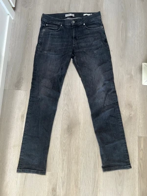 Mörkgrå slim fit jeans från C&A - Snygga mörkgrå slim fit jeans från C&A med klassisk femficksmodell och normal midja. Jeansen har en lätt tvättad look och raka ben. Tillverkade i mjuk och stretchig denim för extra komfort.
