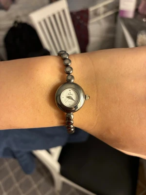 Silverfärgad vintage damklocka - Stilren vintage damklocka med rund urtavla och armband i silverfärgade metallkulor. Urtavlan är vit med diskreta markeringar och Omega-logga. Klassisk och elegant design som passar till många stilar. Skriv ⭐️ i meddelande för hemlig rabbat.