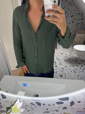 Grön linneskjorta med knappar - Snygg grön skjorta i linne med klassisk krage och knäppning framtill. Skjortan har lång ärm och en avslappnad passform, perfekt för en stilren och chill look.