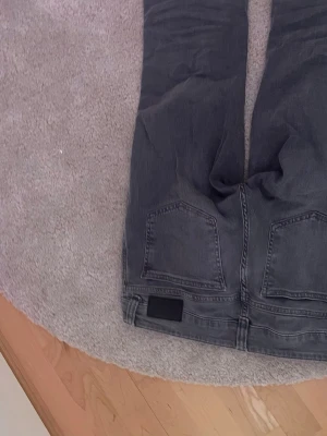 Gråa skinny jeans - Säljer ett par gråa skinny jeans med klassisk femficksdesign och svarta detaljer vid linningen. Jeansen har smal passform och är tillverkade i stretchigt denimtyg för extra komfort.
