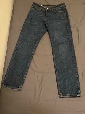Mörkblå raka jeans från Jack & Jones - Säljer ett par mörkblå jeans från Jack & Jones med klassisk rak passform. Jeansen har fem fickor, gylf med dragkedja och knapp samt kontrastsömmar. Tillverkade i denim med en snygg tvättad look. Strl W30 L32