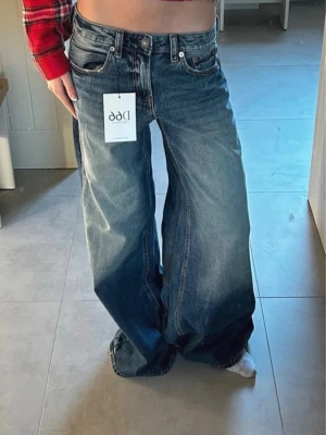 Baggy jeans swag stockholm streetwear - Säljer ett par blå jeans från D66 med riktigt breda ben och hög midja. Jeansen har klassisk femficksdesign, slitningar och en snygg tvättad look. Perfekta för dig som gillar baggy och avslappnad stil.