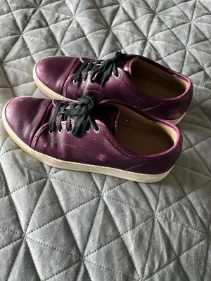 Lanvins  - Snygga vinröda sneakers i läder med svarta snören och vit sula. Skorna har en klassisk låg modell och stilrena sömmar längs sidorna. Perfekta för dig som gillar en enkel men cool look.