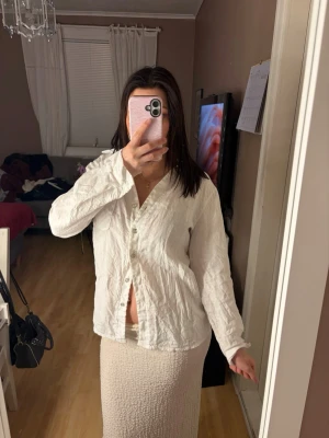 Vit linneskjorta med knappar - Snygg vit skjorta i linne med klassisk krage och knäppning framtill. Skjortan har lång ärm och en avslappnad passform som ger en chill vibe. Perfekt att styla med jeans eller kjol för en enkel men trendig look. Köpt från designbysi och aldrig använd därav är den skrynklig 