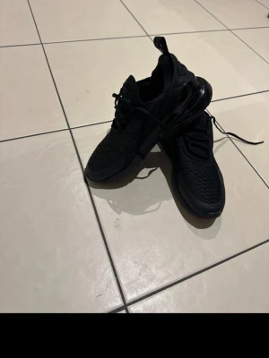 Svarta Nike 270 37.5 helt nya - Säljer ett par helt oanvända helsvarta Nike 270 sneakers. Skorna har klassisk snörning, dragflik bak och sportig design. Perfekta för dig som gillar streetwear och vill ha bekväma sneakers med modern look.