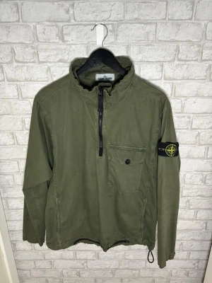 Stone Island overshirt - Stone Island overshirt/anorak i militärgrön färg. Riktigt clean och ovanligare modell med half zip, badge på armen och justerbar passform. Väldigt fint skick.