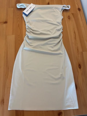 Ljusbeige klänning från Samsøe Samsøe - Ny, oanvänd klänning, perfekt till sommarens fester, t.ex. studenten. Storlek: Small. Etiketterna finns fortfarande kvar. Dansk design: Samsøe Samsøe, från årets sommarkollektion 2026. Se länk! Säljs pga. att ägaren hittat en annan klänning i stället, efter returtiden. Ursprungspris: 1700. 