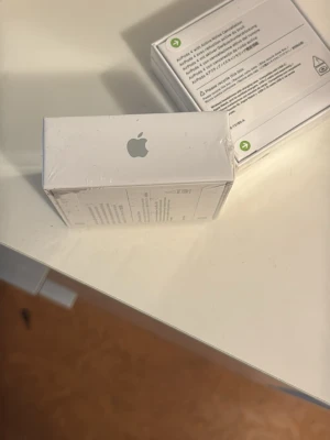 Apple AirPods 4 - Säljer ett par vita Apple AirPods med tillhörande laddningsetui. Trådlösa hörlurar i stilren design, tillverkade i plast med klassisk Apple-logga på förpackningen. Perfekta för musik, samtal och smidig anslutning till iPhone och andra Apple-enheter.