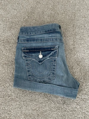 Lågmidjade jeansshorts från True Religion - Säljer ett par blåa lågmidjade jeansshorts från True Religion i storlek w29 med uppvikta benslut. Perfekta för sommaren och riktigt snygga till sneakers eller sandaler. Midjemått tvärsöver: ca 39.5 cm Ytterben: ca 25 cm Priset kan diskuteras! Skriv gärna vid frågor 💞