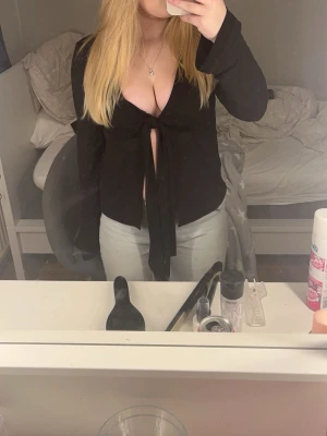 Svart omlottopp med knyt - Svart långärmad omlottopp med djup v-ringning och knyt framtill. Använda ungefär 2 gånger.