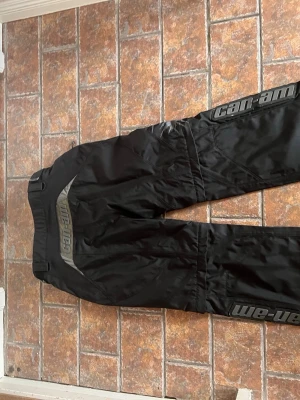Svarta sportbyxor från Can-Am - Säljer ett par svarta täckbyxor från Can-Am med dragkedja så dom blir shorts