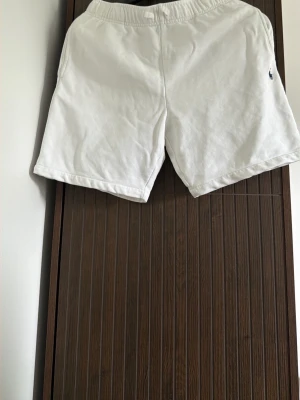 Vita shorts från Polo Ralph Lauren - Snygga vita shorts från Polo Ralph Lauren med elastisk midja och liten broderad logga framtill. Klassisk passform och tillverkade i mjuk bomull, perfekta för sommardagar. Fickor på sidorna och en bakficka för extra stilpoäng.