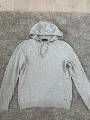 Ljusgrå stickad hoodie från Ragman  - Snygg ljusgrå stickad hoodie från Ragman med dragsko i huvan och ribbade muddar vid ärmslut och nederkant. Tillverkad i mjukt material bomull och kashmir som ger en avslappnad men stilren look. 