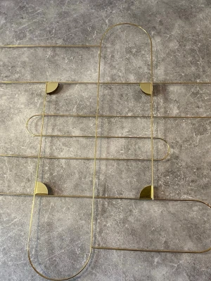 Guldig väggdekoration i metall fotovägg teckningar brev - Snygg väggdekoration i tunn guldfärgad metall med geometriskt, modernt mönster. Passar perfekt som inredningsdetalj för att ge rummet en stilren och trendig känsla. Enkel att hänga upp och blir ett coolt blickfång på väggen.