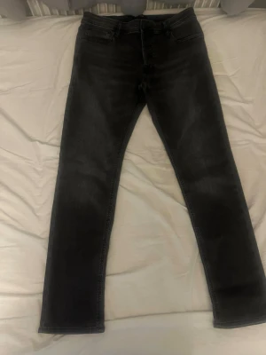 Svarta slim fit jeans - Säljer ett par svarta slim fit jeans med klassisk femficksdesign och normal midja. Jeansen har en snygg tvättad look och raka ben. Perfekta till en avslappnad stil och passar till det mesta. Materialet är troligtvis bomull med stretch för extra komfort.