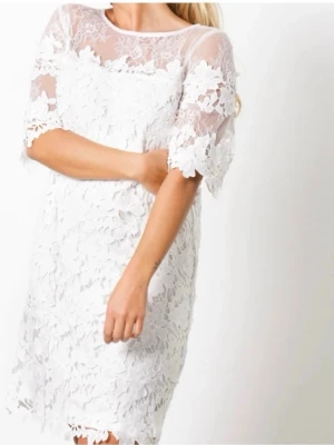 Vit spetsklänning med blommönster - Superfin vit klänning med blommig spets och transparenta partier upptill och på ärmarna. Klänningen har kort ärm och är knälång med en rak passform. Perfekt för sommarens alla tillfällen och studenten eller en skolavslutning 