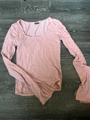 Ljusrosa långärmad topp - Söt ljusrosa långärmad topp med rundad urringning. Tillverkad i mjuk bomull som känns skön mot huden. Perfekt att styla med jeans eller kjol för en enkel och fräsch look.
