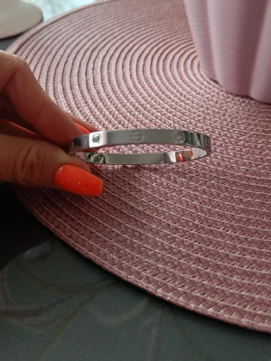 Silverfärgat stålarmband med stenar - Snyggt och stilrent armband i silverfärgat stål med infällda små stenar runt om. Armbandet har en klassisk, rundad form och blanka ytor som ger en modern look. Armbandet är 6 cm i diameter. Nickelfritt. Nytt oanvänd 