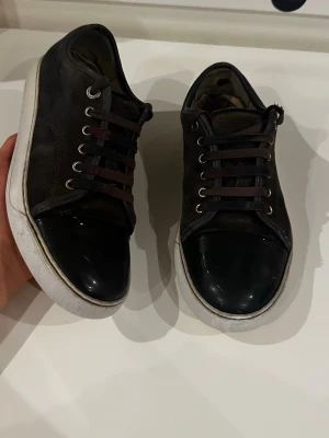 Lanvin skor DBB1 cap toe - Bruna mockaskor med cap toe från Lanvin, modell DBB1, storlek UK 6 (ungefär EU 40–41). Skorna är i bra skick, med två mindre defekter: ett hål på hälarna som inte märks tack vare en tunn extra sula, samt en liten slitning bak på skon som knappt syns. Nypris ligger på 4499 kr. Inga originaltillbehör medföljer.  Kolla gärna in profilen också, där finns flera märkeskläder och skor – du hittar säkert något mer som passar 😉💯 Hör av dig om du undrar något