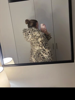 Leopardmönstrad pälsjacka med huva - Säljer en fluffig och trendig pälsjacka med leopardmönster i beige och svart. Jackan har en stor huva och är gjord i fuskpäls som känns riktigt mjuk. Perfekt för dig som vill sticka ut och hålla dig varm med stil💗Orginalpris är 800kr