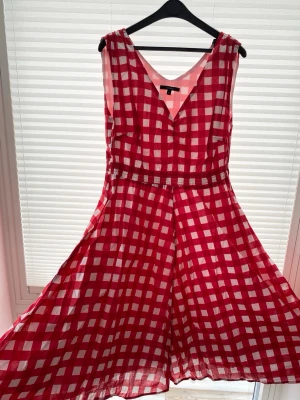 Rutig sommarklänning från Lindex - Säljer en rödvit rutig klänning från Lindex i storlek 42. Midiklänning med v-ringning, markerad midja och ett luftigt, svängigt tyg. Perfekt för sommarens alla tillfällen och har en klassisk, retroinspirerad look. Mycket bra skick. 