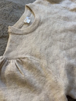 Beige stickad tröja med puffärmar från Gina💕 - Supersöt beige stickad tröja från Gina Young med trendiga puffärmar och ribbade muddar vid hals, ärmslut och nederkant. Tröjan har en mjuk och skön känsla, perfekt för lager på lager. Enkel att matcha till olika outfits. Den är endast provad så typ helt ny i skicket! Den är i storlek 170 vilket motsvarar S som jag har💕💕hör gärna av er vid intresse
