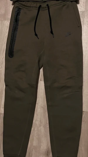 Olivgröna Nike tech byxor - Säljer dessa olivgröna nike tech byxor i storlek S. Använt fåtal gånger så inga problem på den.