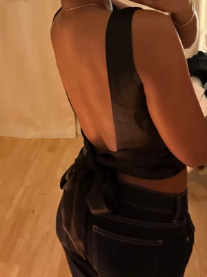 Svart topp öppen rygg  - Så fin satintopp med öppen rygg som man knyter bak. 