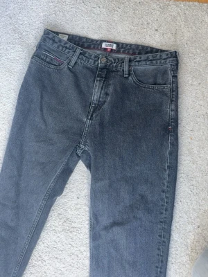 Gråa Tommy Jeans denimjeans - Säljer mina Tommy jeans, de är limited edition och köpte dom för 1,700kr så det är väldigt prisvärt. Säljer de för att de inte längre passar mig.