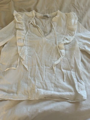 Vit blus med volanger och knytband - Söt vit blus från Kappahl i storlek s men skulle säga att den är mindre i storleken mer xs.
