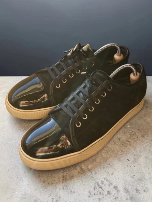 Svarta sneakers med glans  - Svarta lanvins med glans} Uk size 7 motsvarar storlek 41 passar 42} Box ingår, dustbag kan kanske lösas.} skick 9/10 ena snöret har en liten liten defekt, går enkelt att fixa.