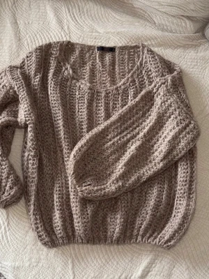 Beige chunky stickad tröja - Säljer en beige chunky stickad tröja med breda ribbade ränder och rund hals. Tröjan har lång ärm och en loose fit som ger en avslappnad vibe. Perfekt för lager på lager under kyliga dagar.