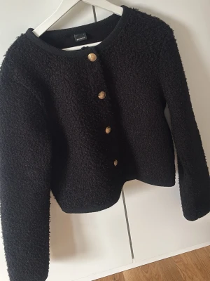 Svart jacka med guldknappar - Classy teddy jacka från Gina 