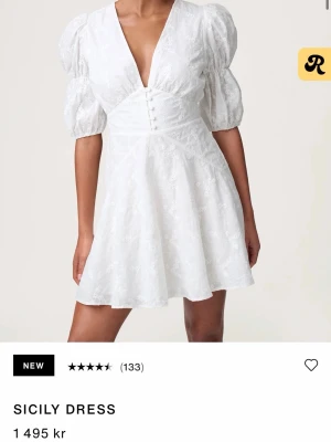 Vit Sicily klänning från Adooee - Supersöt vit Sicily klänning från Adoore med v-ringning och knappar framtill. Klänningen har blommigt mönster i tyget och markerad midja. Perfekt för sommarens alla tillfällen. Köpt till studenten men fel storlek för mig därför jag säljer!