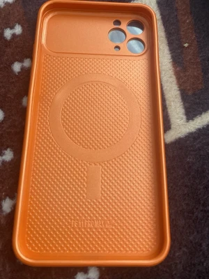 Orange MagSafe skal till iPhone 11 Pro Max - Snyggt orange mobilskal med MagSafe-kompatibilitet för iPhone 11 Pro Max. Skalet har en slimmad design med markerad cirkel för MagSafe och exakta utskärningar för kamera och knappar. Tillverkat i tålig plast som skyddar mobilen mot repor och stötar.