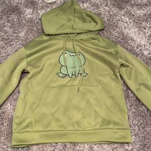 En hoodie med en groda på i grönt från esty använd 1 gång 