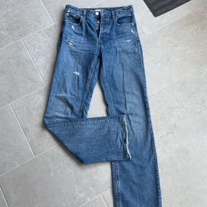Blåa jeans med slitningar  - Fin blå färg (snyggare i verkligheten). Små slitningar (ska vara så). Jättefint skick!