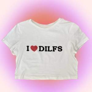 Vit babytee med ”I❤️DILFS” tryck, lite see through och rätt så tajt men med lite stretch. Skulle nog säga att den är liten i storleken så passar mer en mindre M till S💞