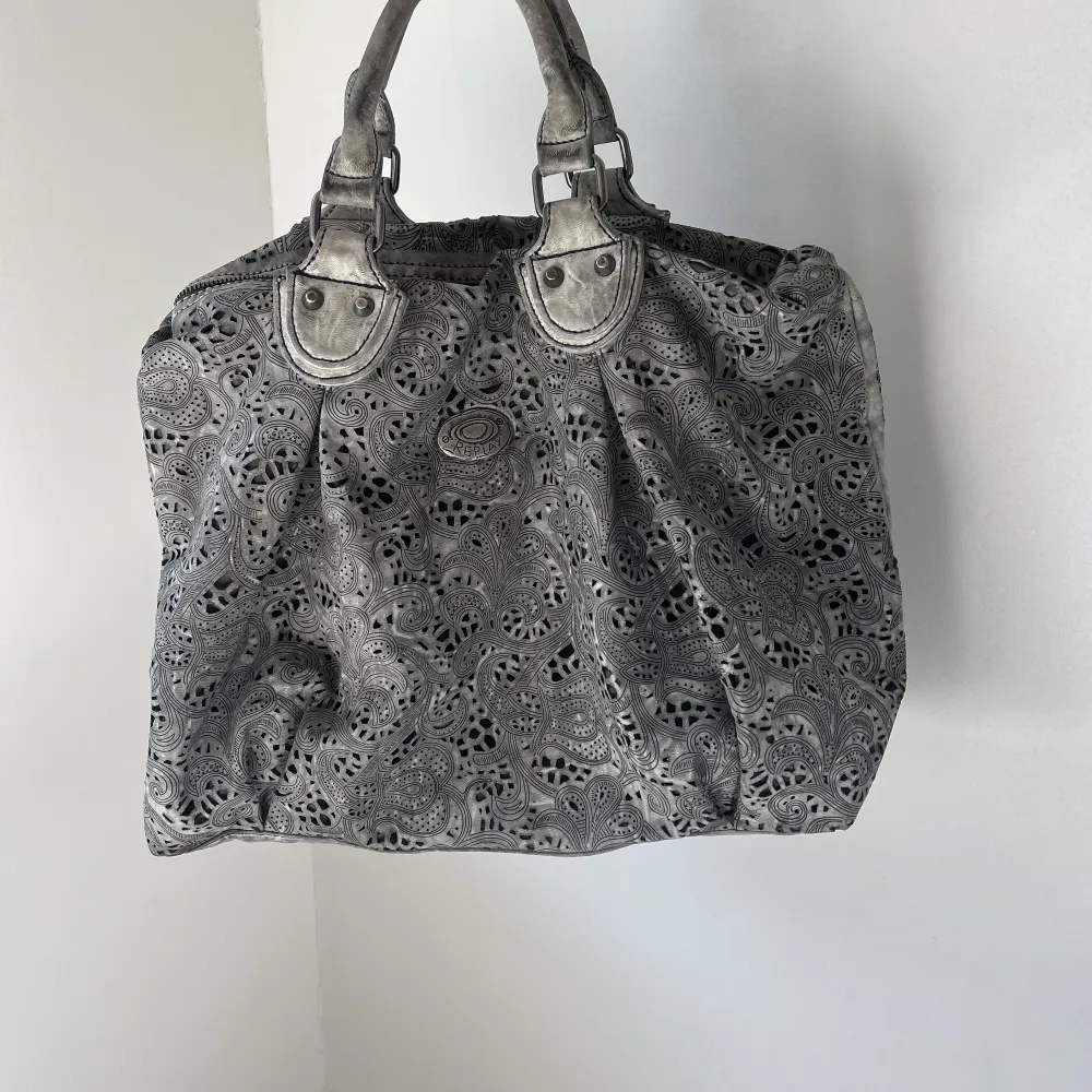 Galet cool väska i grå skiftande färg och unikt mönster. Längre band medföljer. . Väskor.