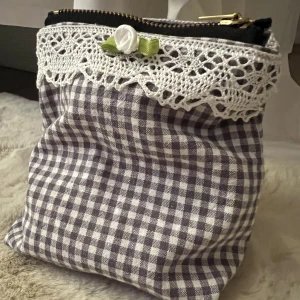 Necessär  - En grå och vit handgjord necessär med söta detaljer samt dragkedja längst upp. Får plats med allt ifrån smink till bindor. Måtten är:  Höjd : 14cm  Bredd (mitten): 9cm Bredd (på botten):9cm Gjord i bomullstyg. Ligger även ute på tradera. Så skriv först:)