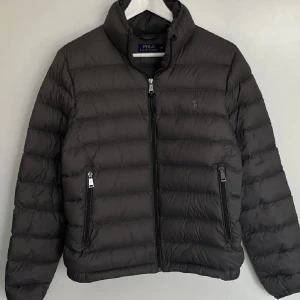 Ralph Lauren Jacket - Ralph Lauren jacka grå puffer jacka. Storlek är M men den har en mindre pass form så skulle säga att den passar bättre som storlek S. Köpt här på plick men inte alls använd eftersom att den var för liten. Skriv för fler frågor.