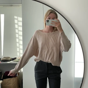 Stickad tröja med rosett - Ljusrosa/beige färg. Lite sliten i nederkant annars bra skick. Väldigt mjuk och mysig i materialet