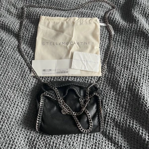 Stella McCartney väska - Säljer min stella McCartney väska falabella tiny tote (minsta modellen). I bra skick, kedjan är missfärgad på vissa ställen. Har både äkthetsbevis och dustbag. Skriv vid fler bilder eller frågor❤️