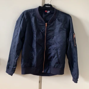 Bomberjacka - En blå bomberjacka med ficka på armen. Använd fåtal gånger men har inget slitage. 