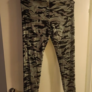 Gröna kamouflagemönstrade leggings  - Materialet är polyester, men de känns väldigt mjuka. Sparsamt använda. Midjemått ca 70cm, längd ca 104cm.