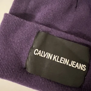 Calvin Klein mössa - Lila Calvin Klein mössa, använd fåtal gånger.