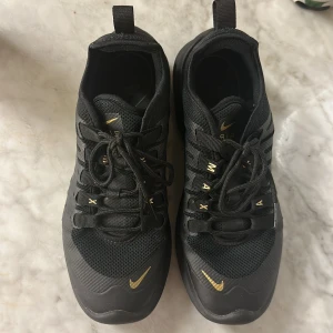 Modellen av dessa skor är: Nike Air Max Axis 'Black Metallic Gold' AA2168-00 (Women’s) - Köpte dessa skor på stadium för 1200 kronor, men jag säljer dem nu, eftersom jag råkade köpa för stor storlek. Dessa skor har jag använt cirka 4 gånger och därav är de i fint skick. De är sköna och passar utmärkt för den som vill ha bekväma + fina skor. 